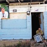 Pancarta de Oscar Arias. Johnny Tenorio, de Cinco Esquinas, repara catres y espera "mucho" del gobierno de Arias.